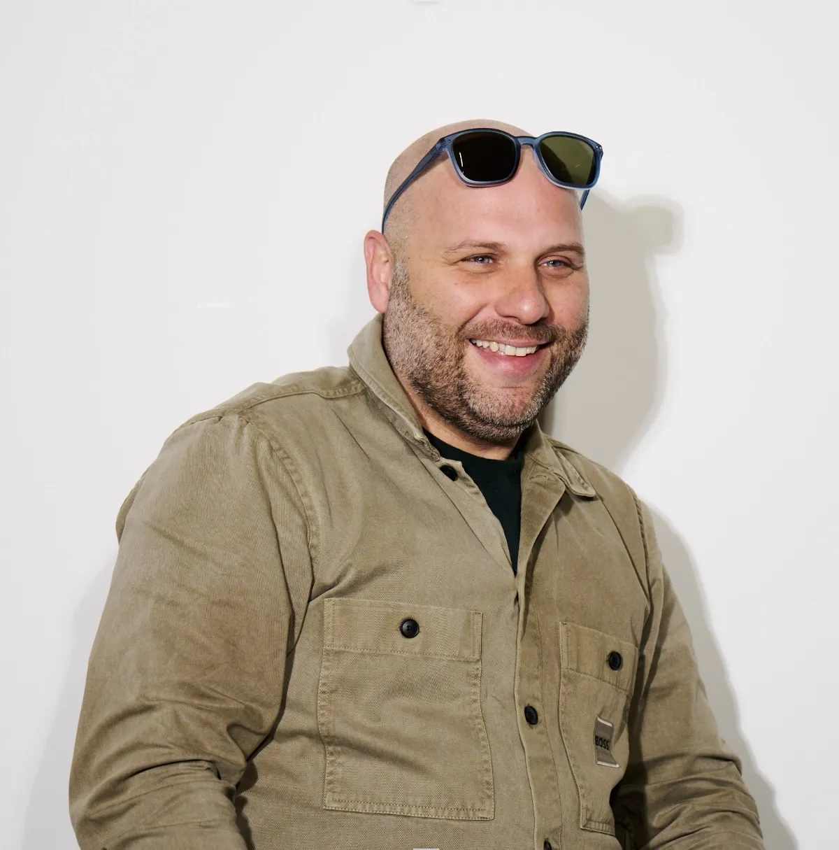 a picture of a man wearing sunglasses and an olive overshirt